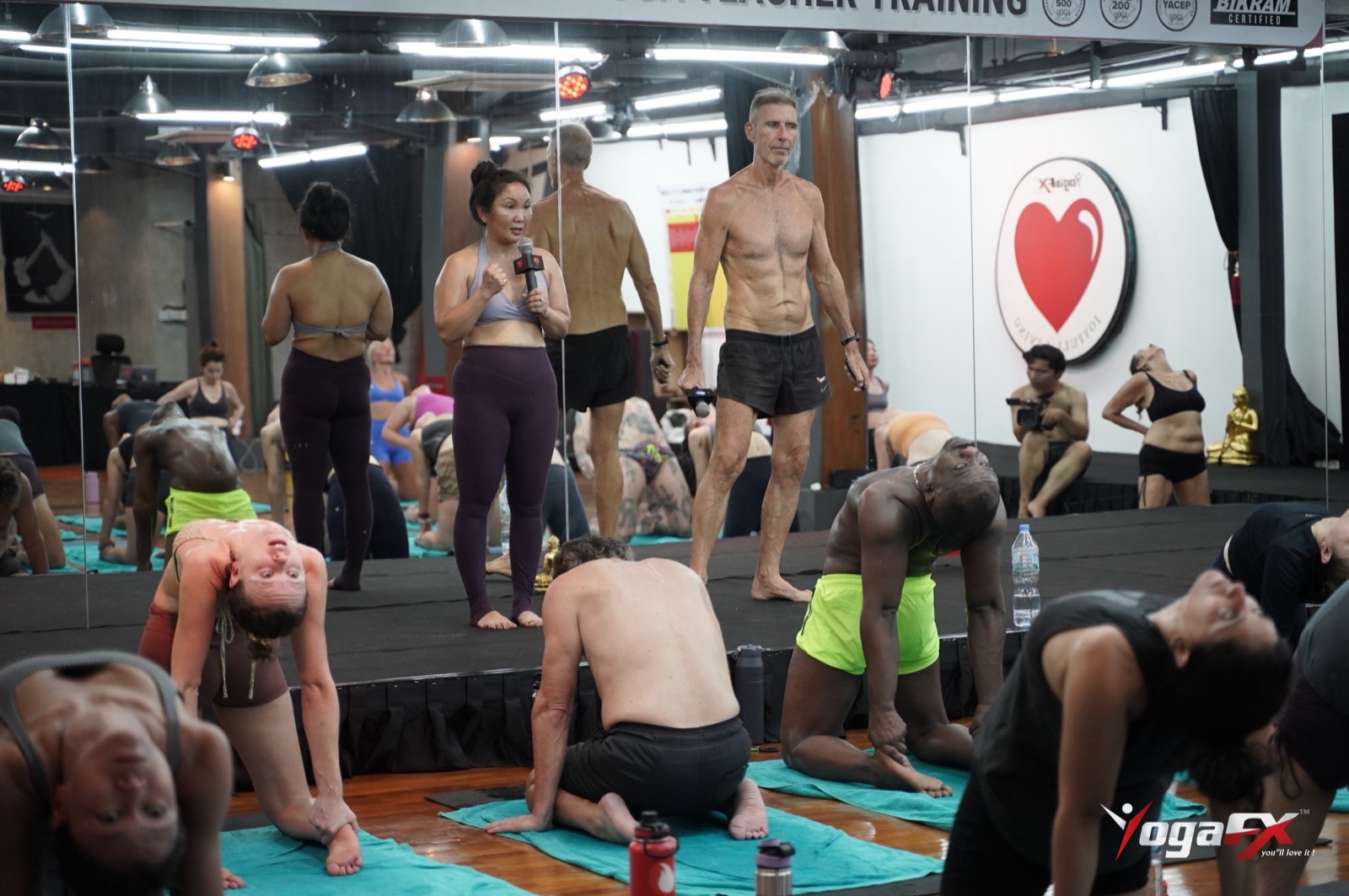 A teacher guiding students through a full heated 26 and 2 class, a hard session that is best kept apart from yoga for athletes recovery days